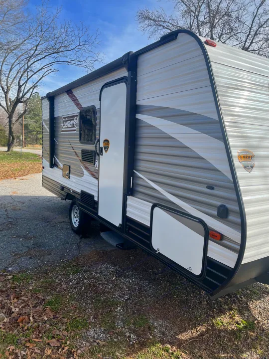 Coleman travel trailer, perfect for your next RV rental. Features an awning, side door, and storage, parked outdoors.. Dutchmen Coleman Lantern LT 2019