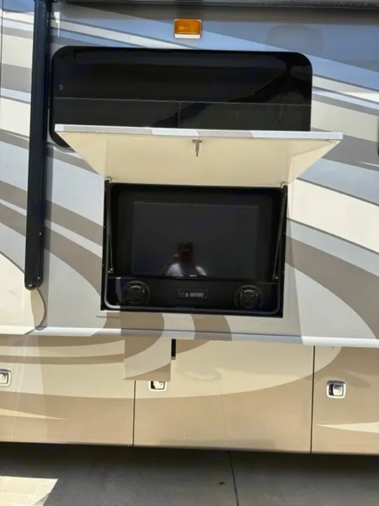 Outdoor entertainment setup on an RV rental, featuring a TV and speakers in an open side compartment.. Holiday Rambler Endeavor 2017