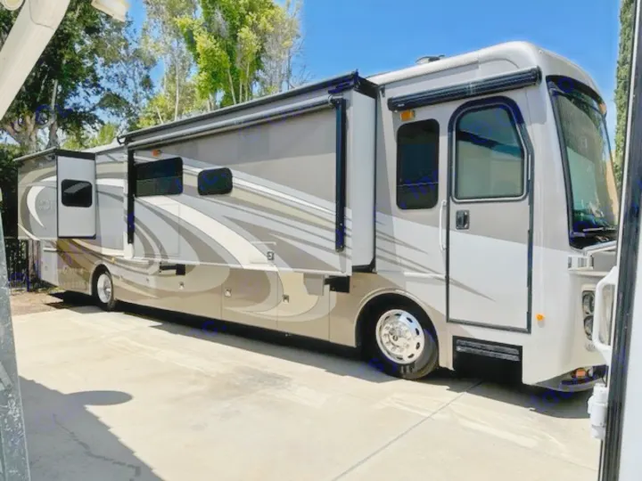 Large, modern gray and tan RV rental with extended slides, parked on concrete, ready for your next journey.. Holiday Rambler Endeavor 2017