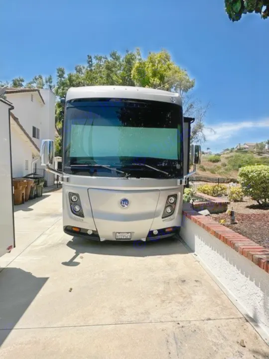 This spacious silver motorhome, ready for RV rental, is parked on a sunny driveway, perfect for your next travel adventure.. Holiday Rambler Endeavor 2017