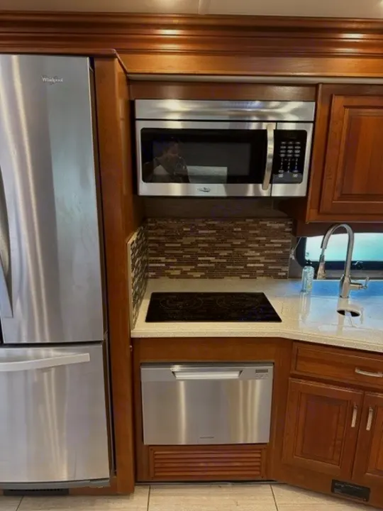 RV rental's modern kitchen boasts stainless steel fridge, microwave, dishwasher, cooktop, and rich wood cabinets.. Holiday Rambler Endeavor 2017