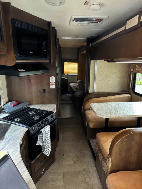 RV rental interior: fully equipped kitchen, spacious dinette, and cozy bedroom in the background, ready for your next adventure.. Forest River Coachmen Freelander 2018