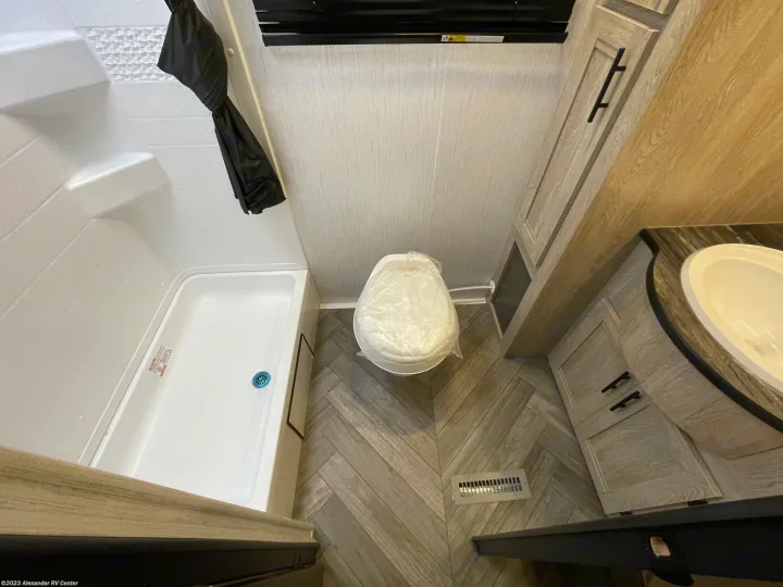 Inside an RV rental's modern bathroom: shower, plastic-covered toilet, and vanity with sink.. Heartland RVs Prowler 2022