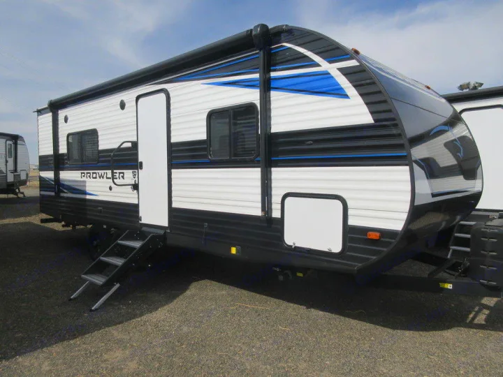 Modern black, white, and blue Prowler travel trailer for RV rental, showcasing its exterior with steps extended on gravel.. Heartland RVs Prowler 2022