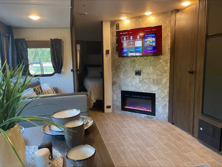 Interior of a modern RV rental with a large smart TV, electric fireplace, and comfortable living/dining areas. Perfect for adventures.. Forest River Cherokee Grey Wolf 2021