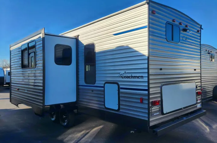 This Coachmen travel trailer, ideal for rv rental, features a silver corrugated exterior with blue accents and a slide-out.. Coachmen Summit series 2023