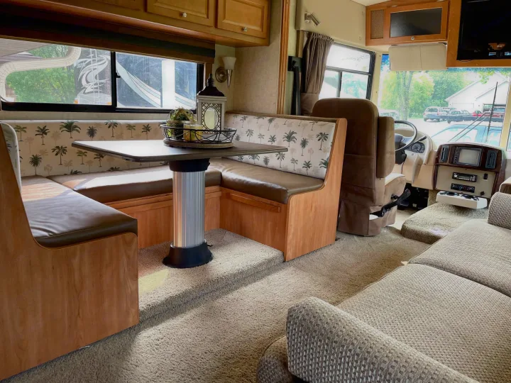 Enjoy this RV rental's cozy interior, featuring a palm tree print dinette, sofa, and cockpit. Perfect for travel!. Itasca Sunstar 2008