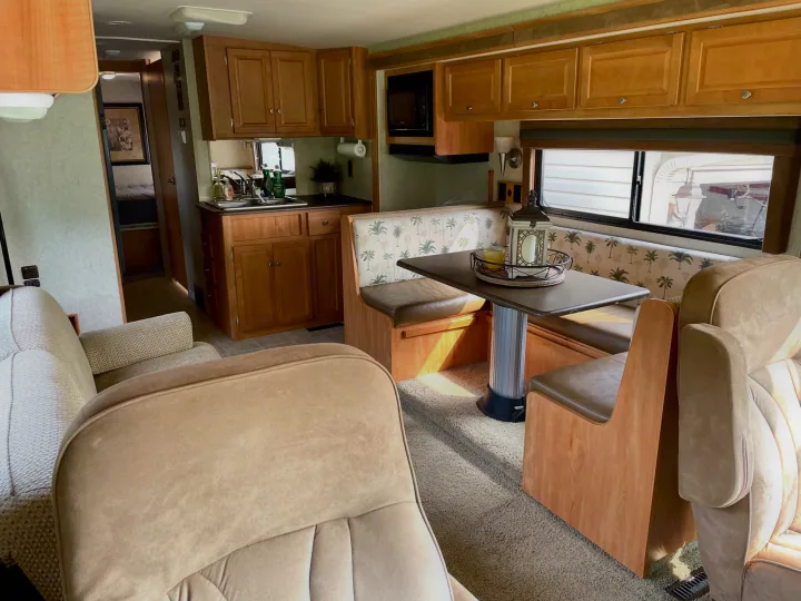 Spacious RV rental interior with a bright kitchen, dinette booth, and comfortable living area. Ideal for travel.. Itasca Sunstar 2008