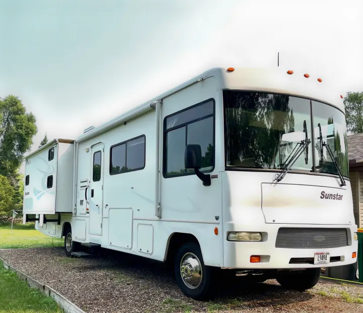 Large white Sunstar motorhome RV rental with slide-out extended, parked on gravel for your next travel adventure.. Itasca Sunstar 2008