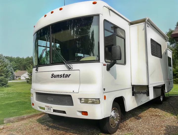 A clean white Sunstar RV motorhome with an extended slide-out, perfect for rv rental. Parked on gravel.. Itasca Sunstar 2008