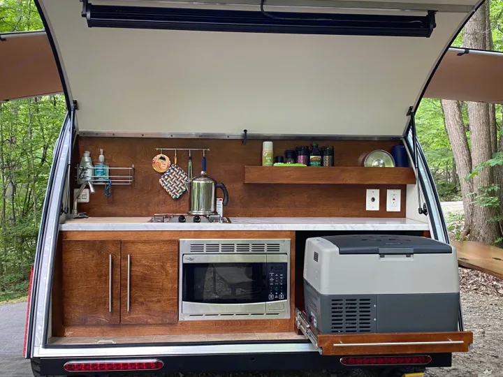 Discover the convenience of this RV rental's outdoor kitchen: sink, stove, microwave, and pull-out cooler in a camper galley.. nuCamp T@G 2019
