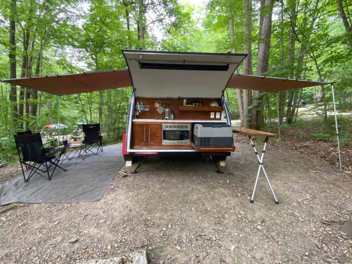 Experience camping comfort: This RV rental teardrop camper boasts a full outdoor kitchen, dual awnings, & cozy campsite setup.. nuCamp T@G 2019