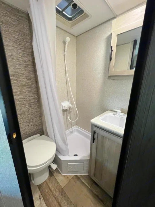 Compact RV rental bathroom with shower, toilet, and vanity sink, viewed from above.. KZ Sportsmen 191BHK 2022