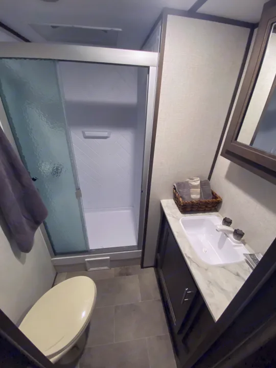 Experience comfort in this RV rental's bathroom. Features a compact sink, enclosed shower with frosted glass, and toilet.. Dutchmen Coleman Light 2021