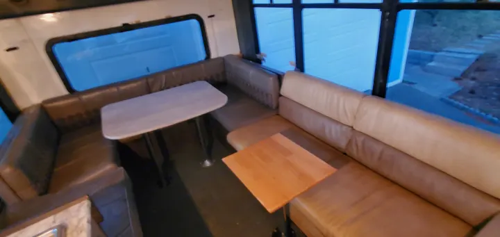 RV rental interior showcasing a cozy dinette with a table and a comfy sofa with its own table, featuring large windows.. Ford E450 2000
