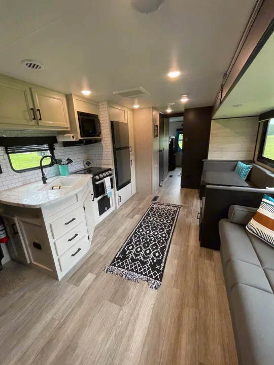 Spacious RV rental interior: kitchen with sink, stove, fridge, and dining/living areas with sofa.. Jayco Jayflight 324BDS 2023