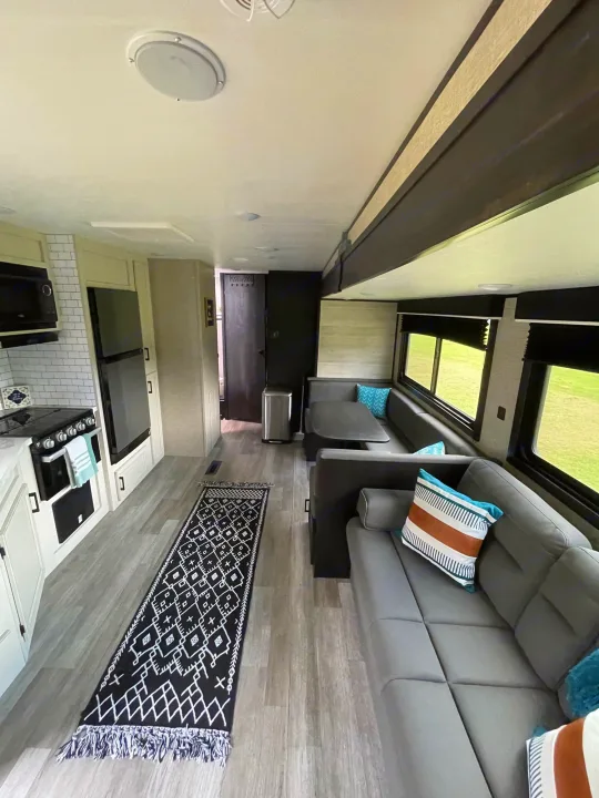 Spacious and modern RV rental interior featuring a full kitchen, dining booth, and comfortable lounge area with a sofa.. Jayco Jayflight 324BDS 2023