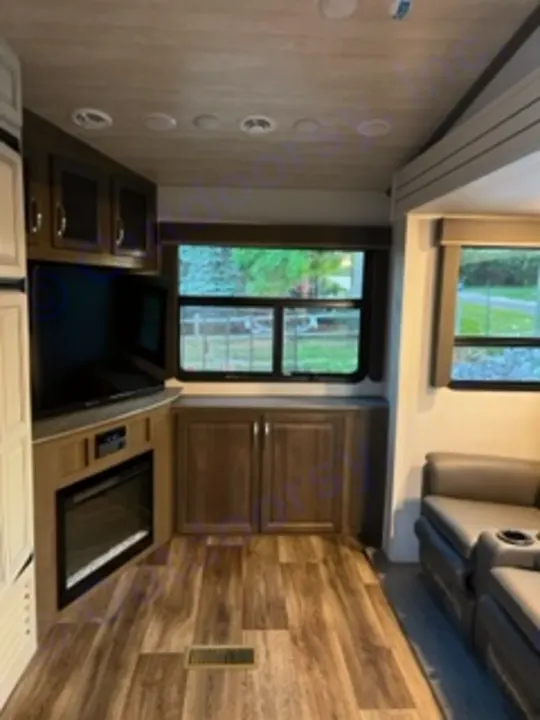 Modern RV rental interior: a spacious living area with recliners, convertible bed, and wood-look flooring, perfect for travel.. Keystone RV Cougar 2022