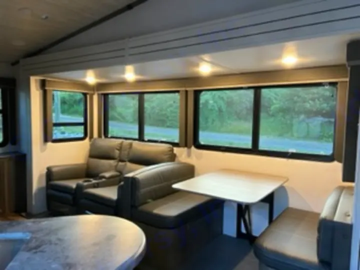This RV rental's inviting living area features recliners, a dinette, and bright windows, ideal for scenic travels.. Keystone RV Cougar 2022