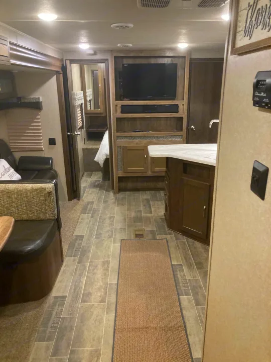 Inside an RV rental: a well-appointed living space with kitchen island, entertainment center, and cozy bedroom. Ideal for trips.. Palomino Puma 31DBTS 2020