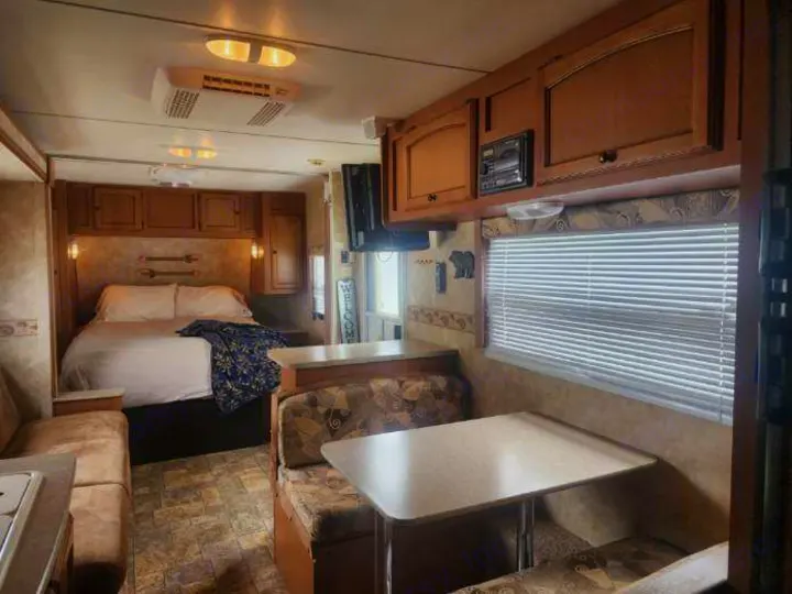 Cozy RV rental interior with a comfortable bed, dinette, and ample overhead storage.. Gulf Stream Stream Lite Sport 2011