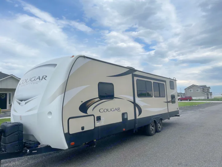 A modern Cougar travel trailer, ideal for your next RV rental adventure. Parked on asphalt under a cloudy sky.. Keystone Cougar Half-Ton 2018