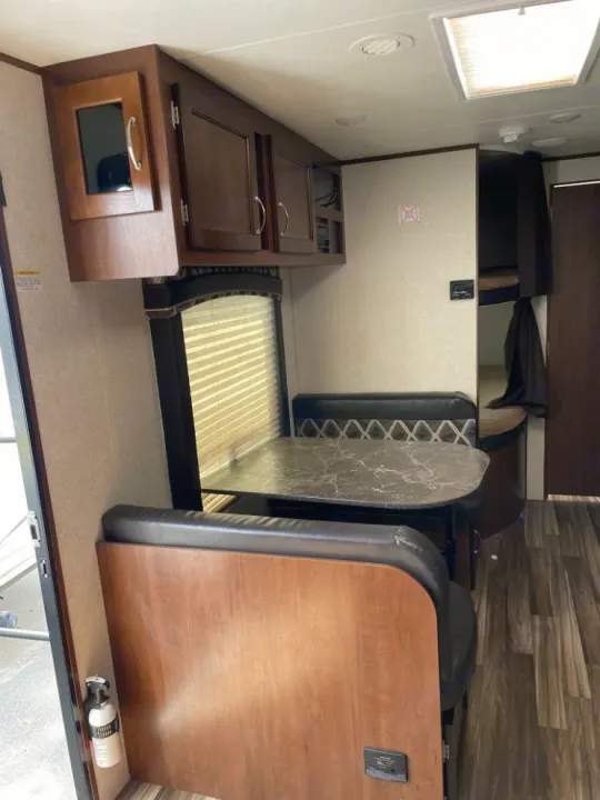Step inside this rv rental: A functional dinette with table, bench seating, and overhead cabinets; bunk beds visible in back.. Jayco Jay Flight 2017
