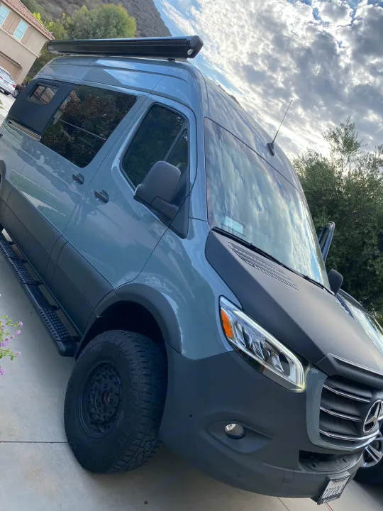 A rugged gray Mercedes Sprinter camper van with a roof awning & off-road tires, great for RV rental.. Mercedes Benz Sprinter 2500 2022