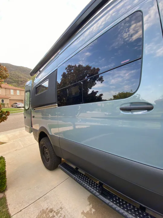 Light blue camper van with tinted windows and a side step on a driveway. Ideal for an RV rental getaway.. Mercedes Benz Sprinter 2500 2022