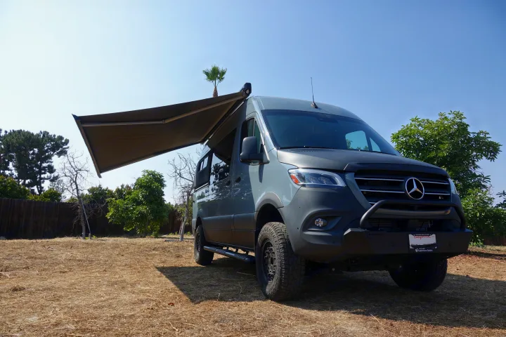 Grey Mercedes Sprinter camper van with extended awning, parked outdoors. Ready for your RV rental adventure.. Mercedes Benz Sprinter 2500 2022