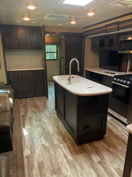 Experience comfort in this modern RV rental. Features a stylish kitchen with dark cabinets, island, and appliances, plus ample living space.. Grand Design Reflection 2022