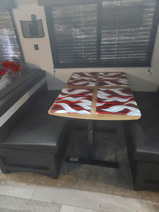 Enjoy meals in this RV rental's dinette, featuring a unique wavy-patterned table and comfy booth seating.. Keystone RV Springdale 2022