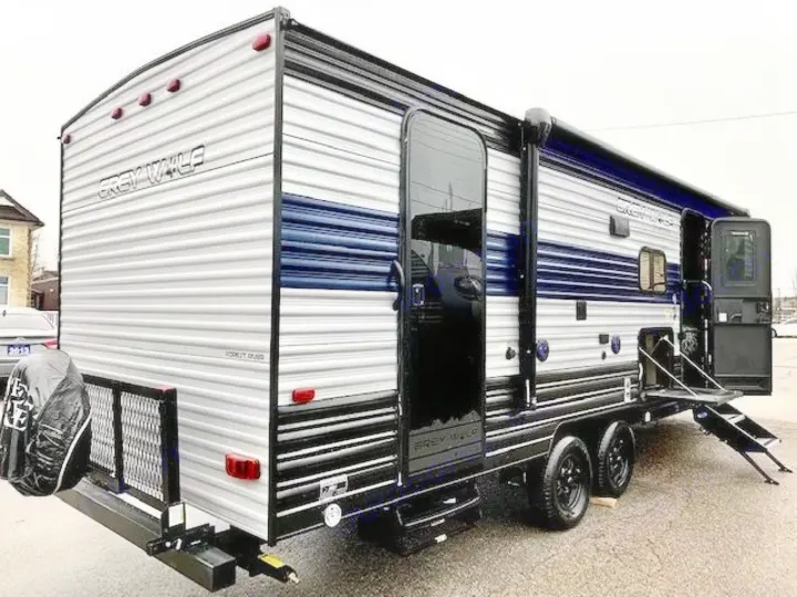 Modern grey and blue Grey Wolf travel trailer, ideal for RV rental. Side door open, steps extended, ready for adventures.. Forest River Cherokee Grey Wolf 2022