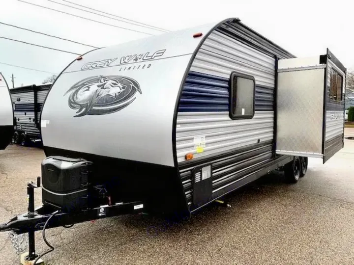 This silver Grey Wolf travel trailer, an ideal RV rental, shows its side with an open slide-out for extra space.. Forest River Cherokee Grey Wolf 2022