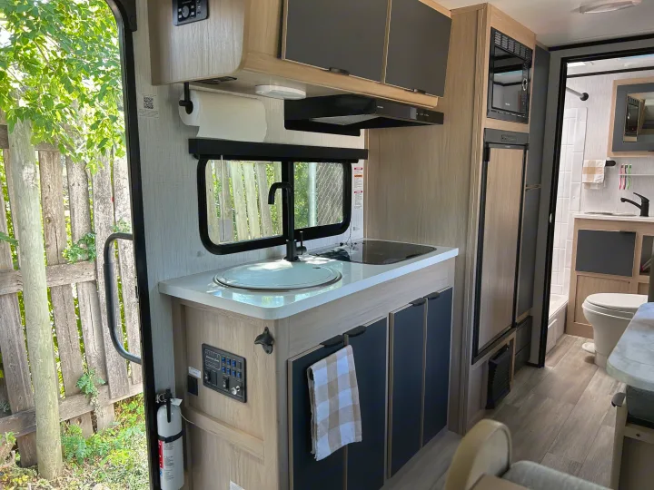 Modern RV rental interior with a fully equipped kitchen, bathroom, and control panel, ideal for travel.. Cruiser RV Hitch 2022