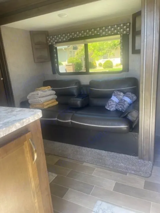 RV rental living area: comfy black recliners, window with outdoor view, wood-look floor, and towels ready.. Dutchmen Coleman Light 2019