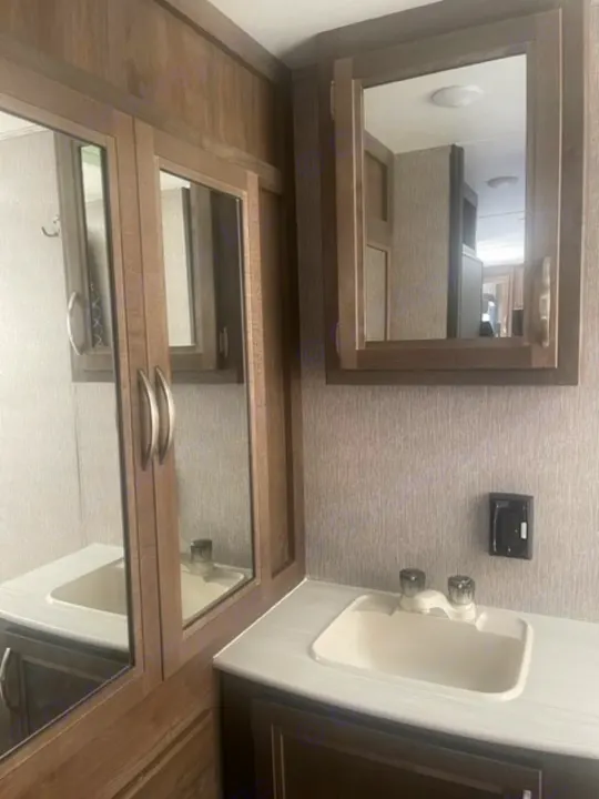 RV rental bathroom with double vanity, two sinks, and ample mirrored cabinetry for storage.. Dutchmen Coleman Light 2019