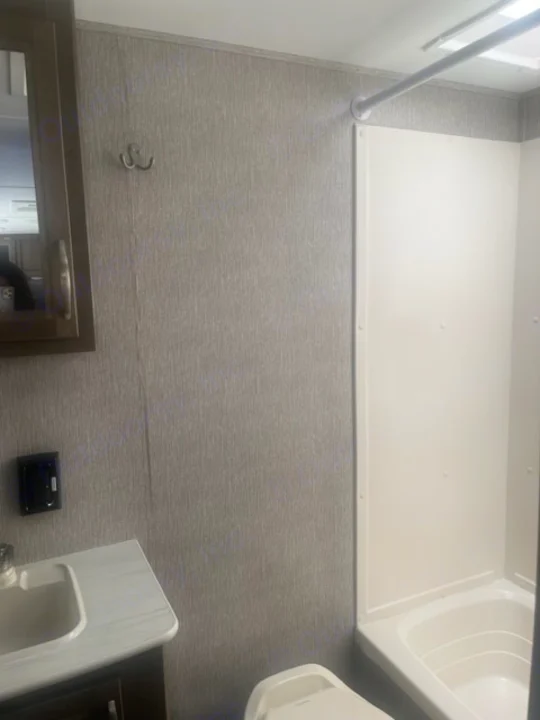 RV rental bathroom features textured grey walls, a sink, toilet, shower, and mirrored medicine cabinet.. Dutchmen Coleman Light 2019
