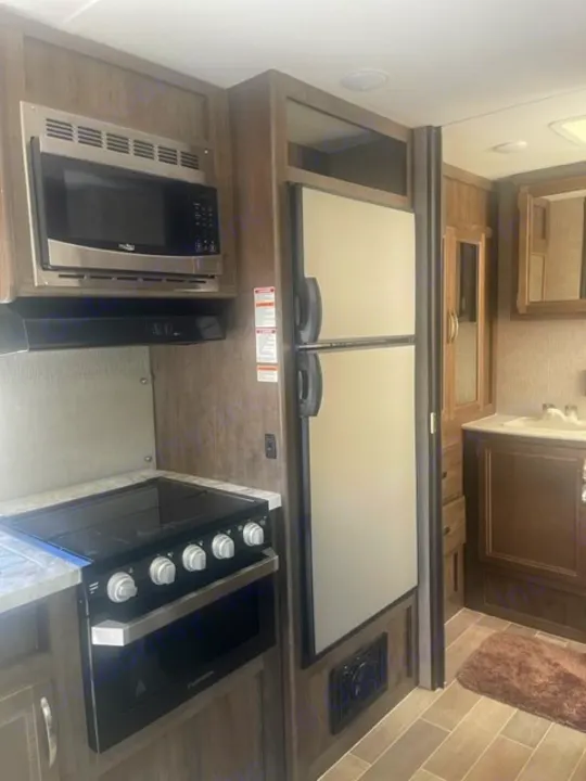 RV rental kitchen showcasing microwave, stovetop, oven, and refrigerator. Functional interior ready for adventure!. Dutchmen Coleman Light 2019