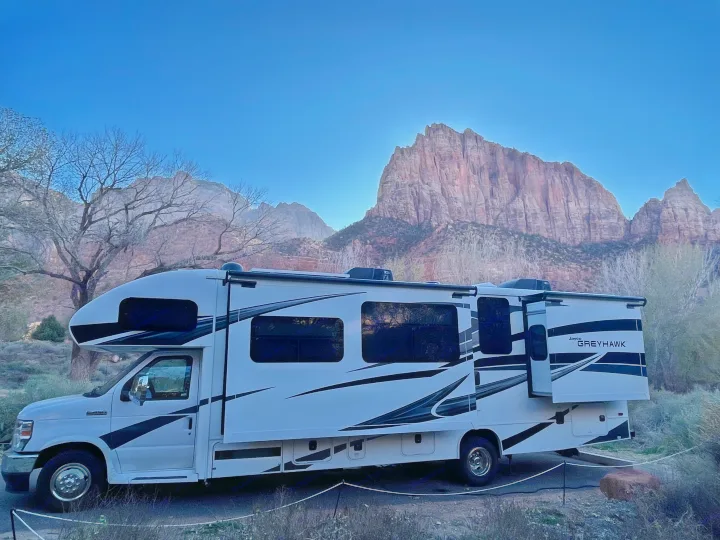 Jayco Greyhawk RV rental parked at a scenic campsite with towering red rock mountains and bare trees under a clear blue sky.. Jayco Greyhawk 2022