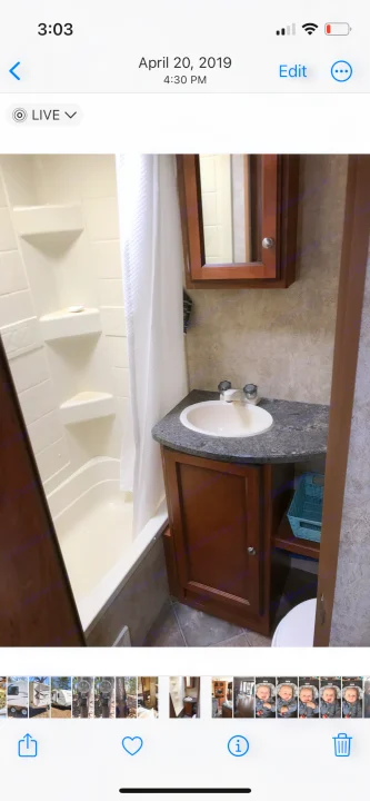 An RV rental's compact bathroom, showing a tub/shower, small sink with dark counter, and wooden storage cabinets.. Keystone RV Passport Ultra 2013