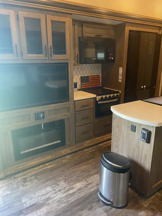 Modern RV rental interior showcasing a full kitchen, TV, and electric fireplace within a cozy living space.. Forest River Sabre 2022