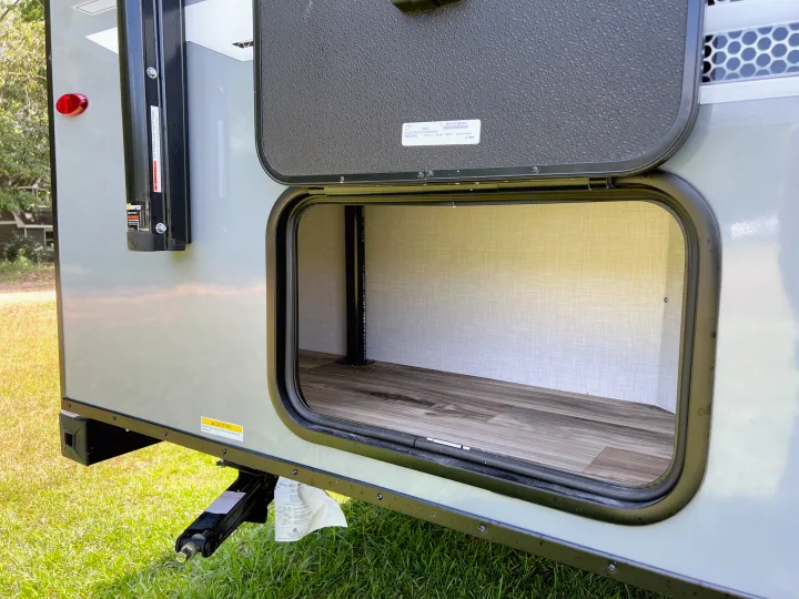 Open exterior storage of an RV rental, revealing a spacious compartment inside a travel trailer for your gear.. Venture Rv Sonic 2023