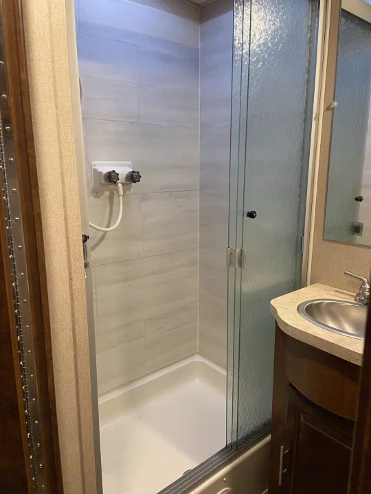 RV rental bathroom: a clean, compact space with a tiled shower, frosted glass door, and a vanity with a sink.. Forest River Fr3 2017