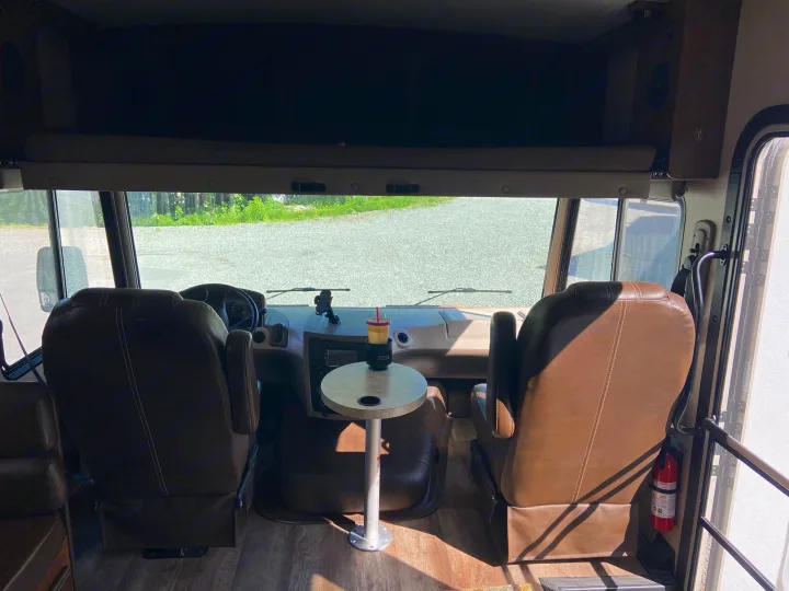 RV rental: Inside the cockpit, showing comfy brown driver and passenger seats, a central table with a drink, and an overhead bunk.. Forest River Fr3 2017