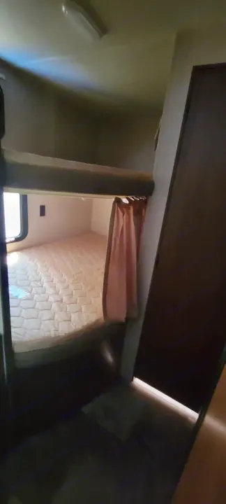 RV rental interior shows compact bunk beds with a patterned mattress and privacy curtain, ideal for sleeping.. Jayco Jay Flight SLX 2015