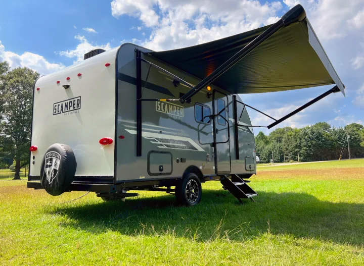 SCAMPER RV rental: a sleek travel trailer with an extended awning, parked in a vibrant green field on a clear day.. Venture Rv Sonic 2023