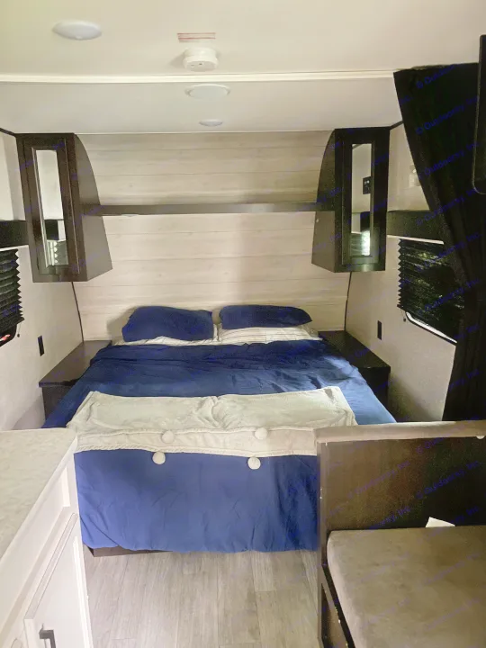 Cozy RV rental bedroom featuring a full bed, overhead storage, and modern wood-panel interior.. Jayco Jay Flight SLX 2022
