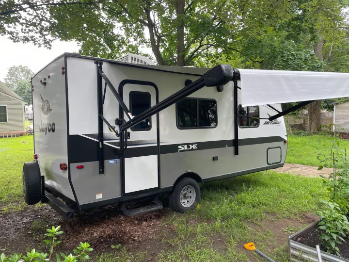 Modern Jayco travel trailer RV rental, grey & white, parked with awning extended in a green yard.. Jayco Jay Flight SLX 2022