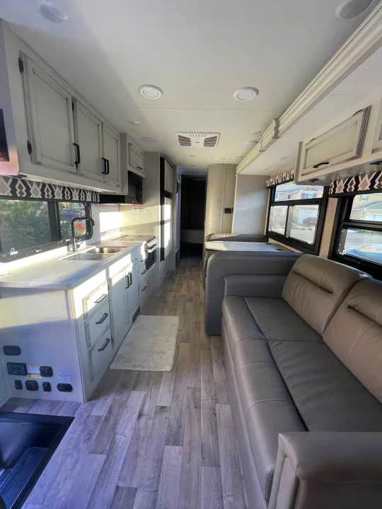 Modern RV rental interior: spacious kitchen, living area with sofa & dinette, wood-look floor.. Jayco Greyhawk 2022